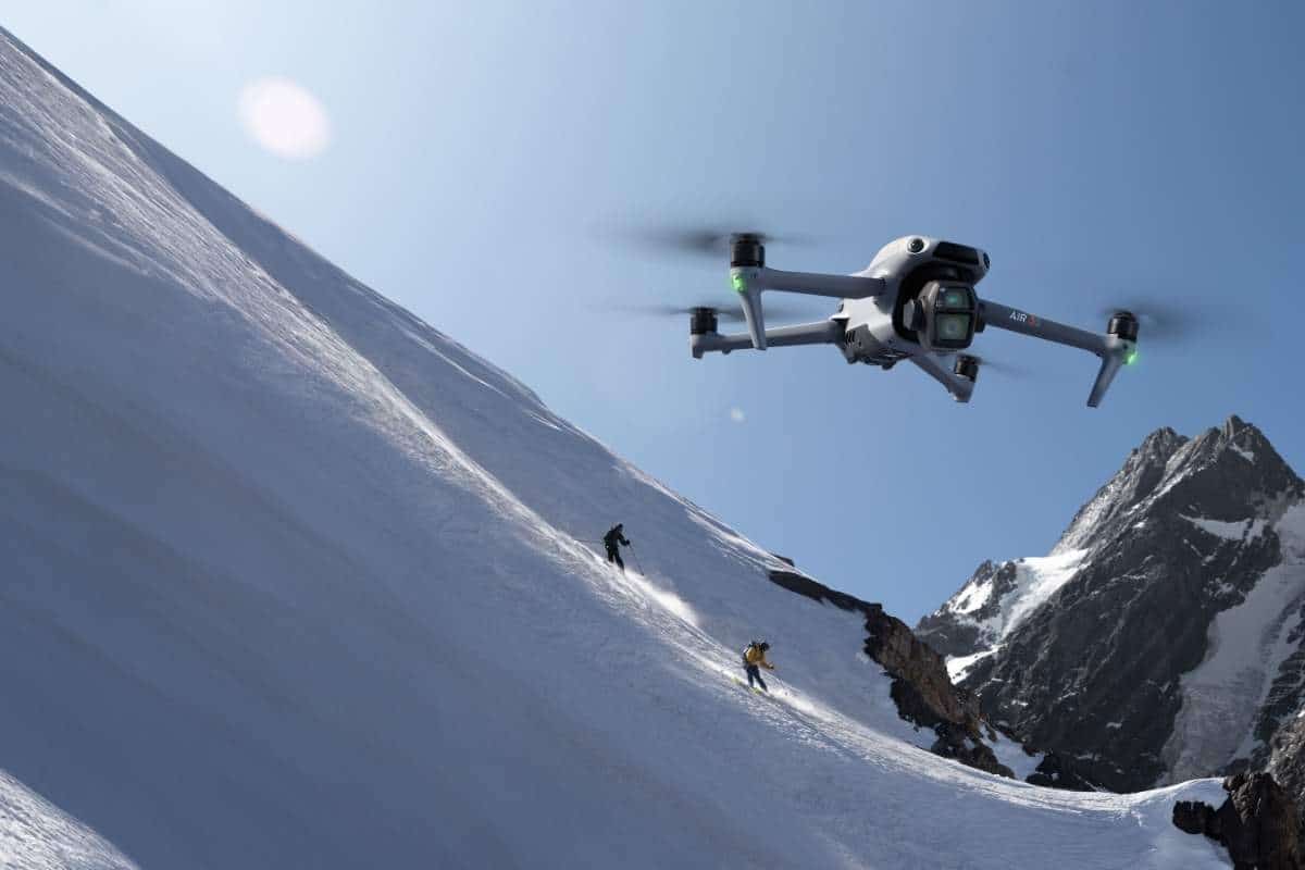 Drone DJI 3s in volo su montagne di neve e sciatori su sfondo