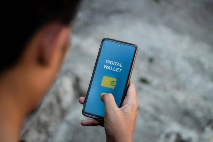 Uomo che guarda cellulare con sfondo digital wallet