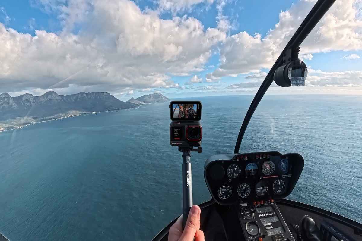 Insta360 Ace Pro 2 in mano su aereo con sfondo mare