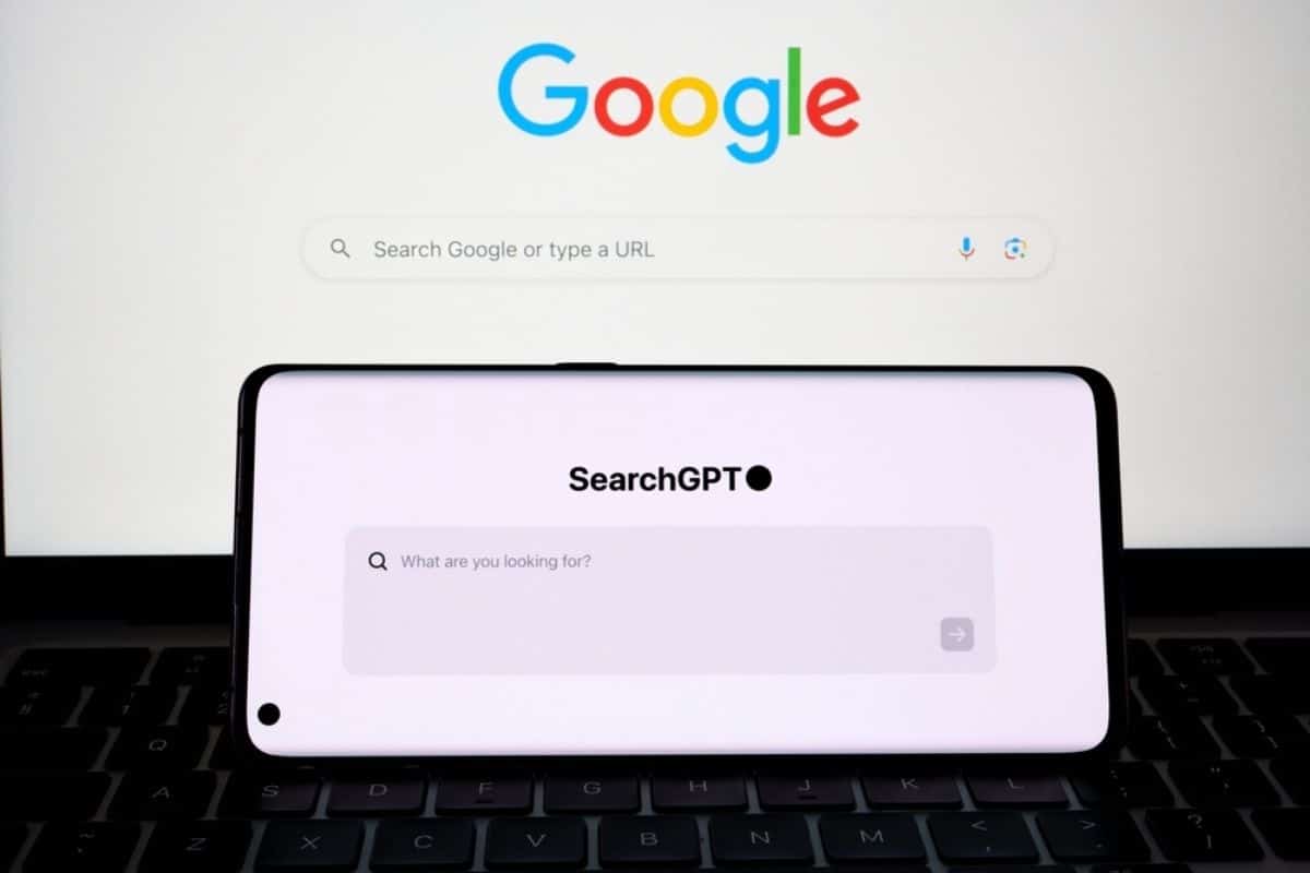 SearchGPT su smartphone e motore di ricerca google su monitor in sfondo